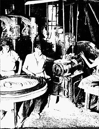 IN MAKING GARDEN HOSE THE RUBBER IS FORMED INTO A TUBE
BY THE MACHINE ON THE RIGHT AND COILED ON THE TABLE TO THE LEFT