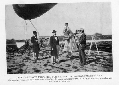 SANTOS-DUMONT PREPARING FOR A FLIGHT IN "SANTOS-DUMONT NO. 6"
The steering-wheel can be seen in front of basket, the motor is suspended in frame to the rear, the propeller and rudder at extreme end.